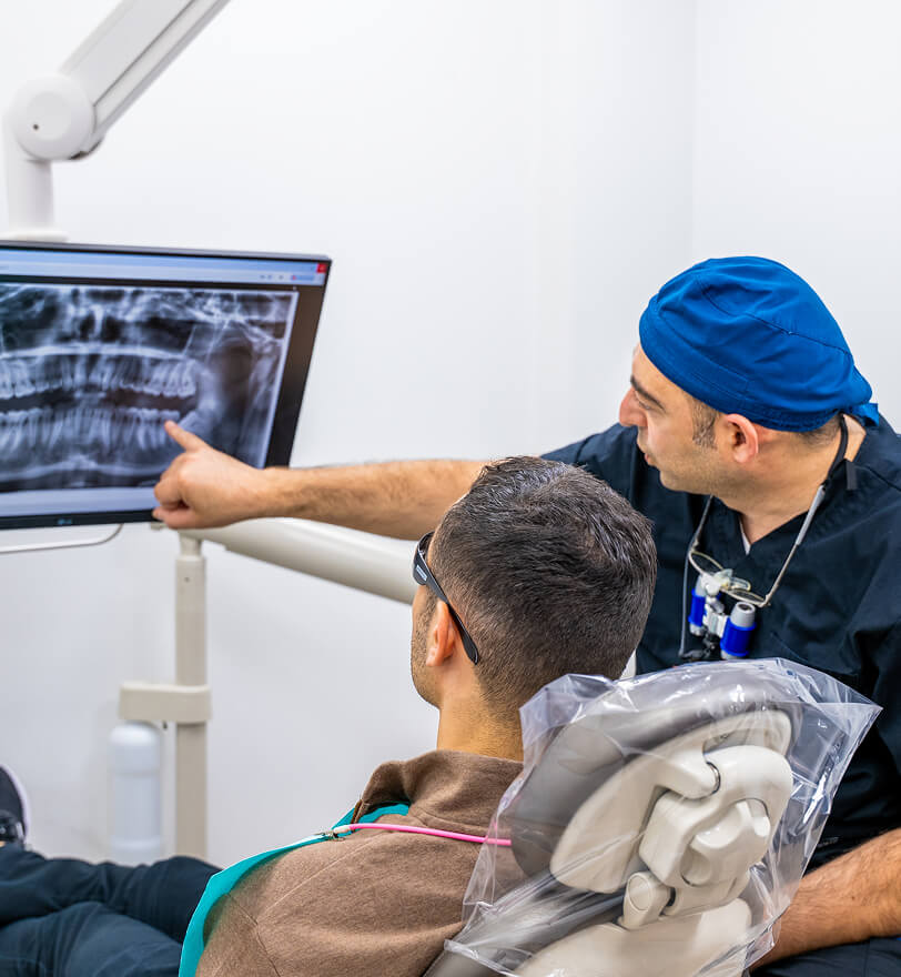 Image of Dr. Alexander Katanov, DMD pointing at an X-Ray while speaking to a patient at the office of Diamond Dental Group in Denver CO.